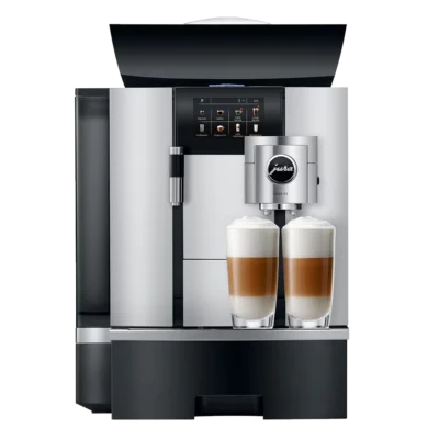 Un JURA GIGA X3c Aluminium (SB) élégant et moderne avec un affichage numérique et deux boissons au café garnies de mousse de lait fumante sur le plateau avant. La machine a un design en acier inoxydable et noir avec le logo de la marque visible sur le mousseur à lait.