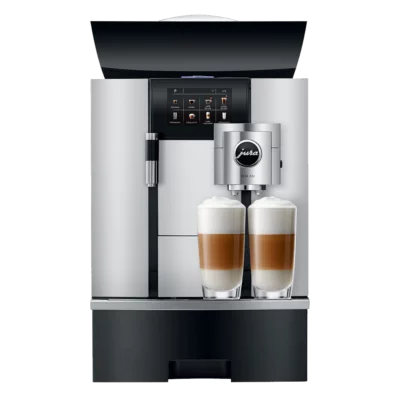 Une machine à café élégante et moderne avec un écran d'affichage numérique et le nom de marque « JURA GIGA X3c Aluminium (SB) » sur le panneau avant. La machine distribue deux tasses de café garnies de lait mousseux.