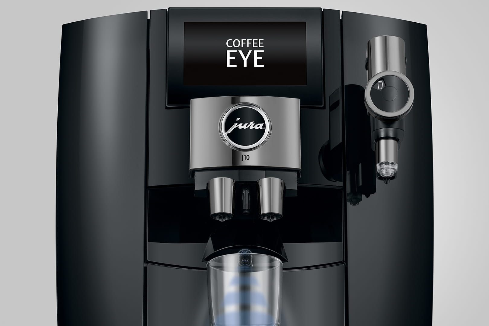 Gros plan d'une machine à expresso moderne avec un écran numérique indiquant « COFFEE EYE ». La machine présente un design noir élégant avec un logo central indiquant « jura J10 ». Sous l'écran se trouvent deux buses et un espace pour placer une tasse.