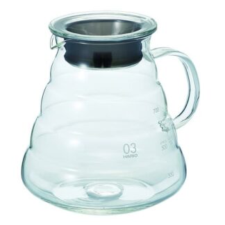 La carafe HARIO pour V60 est une carafe en verre transparent élégante et moderne avec un couvercle en métal et une poignée latérale. Elle comporte des graduations sur le côté pour indiquer différents volumes, ce qui la rend parfaite pour servir des boissons.